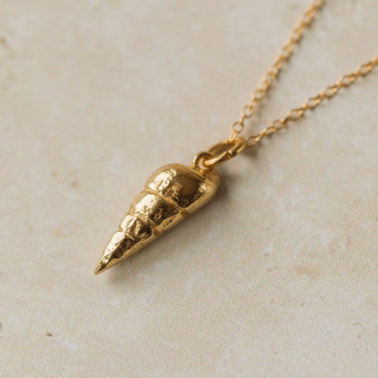 Gold pendant necklace on a light beige surface