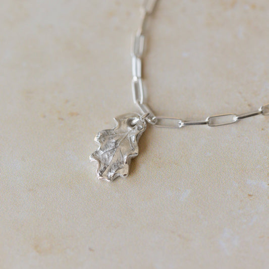silver oak leaf charm bracelet with paperclip chain on neutral stone background, handcrafted recycled silver jewellery by Iris & Lolli
