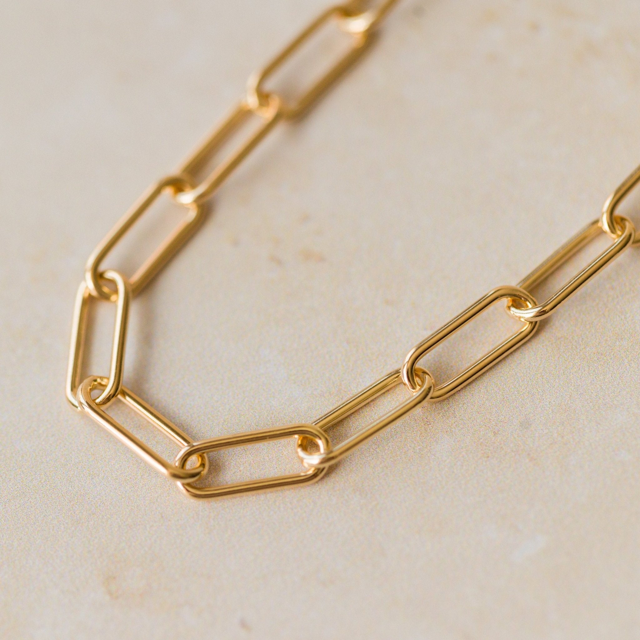 close-up of 18ct gold vermeil chunky paperclip chain bracelet links on neutral background by Iris & Lolli