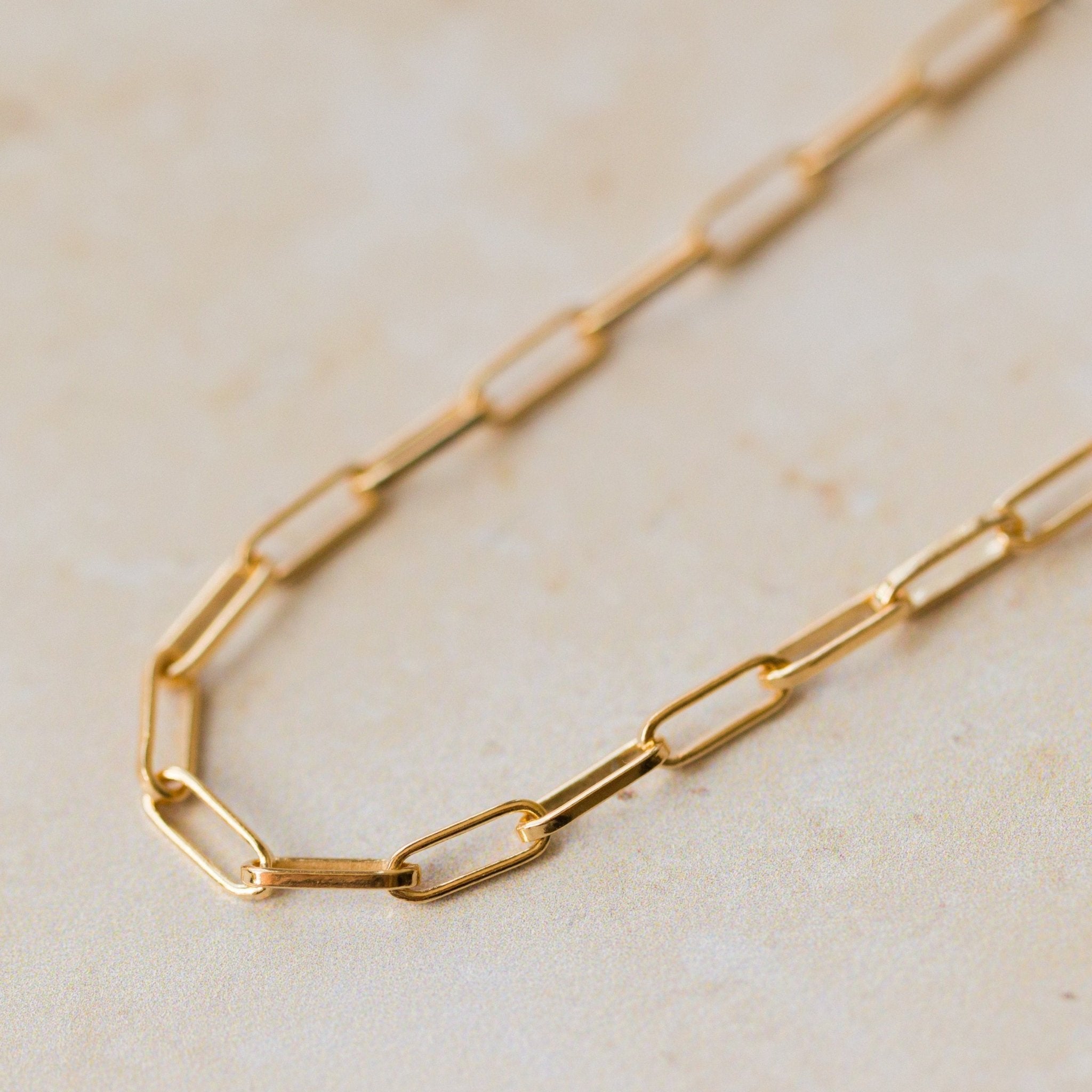 close-up of 18ct gold vermeil fine paperclip chain bracelet links on neutral background by Iris & Lolli