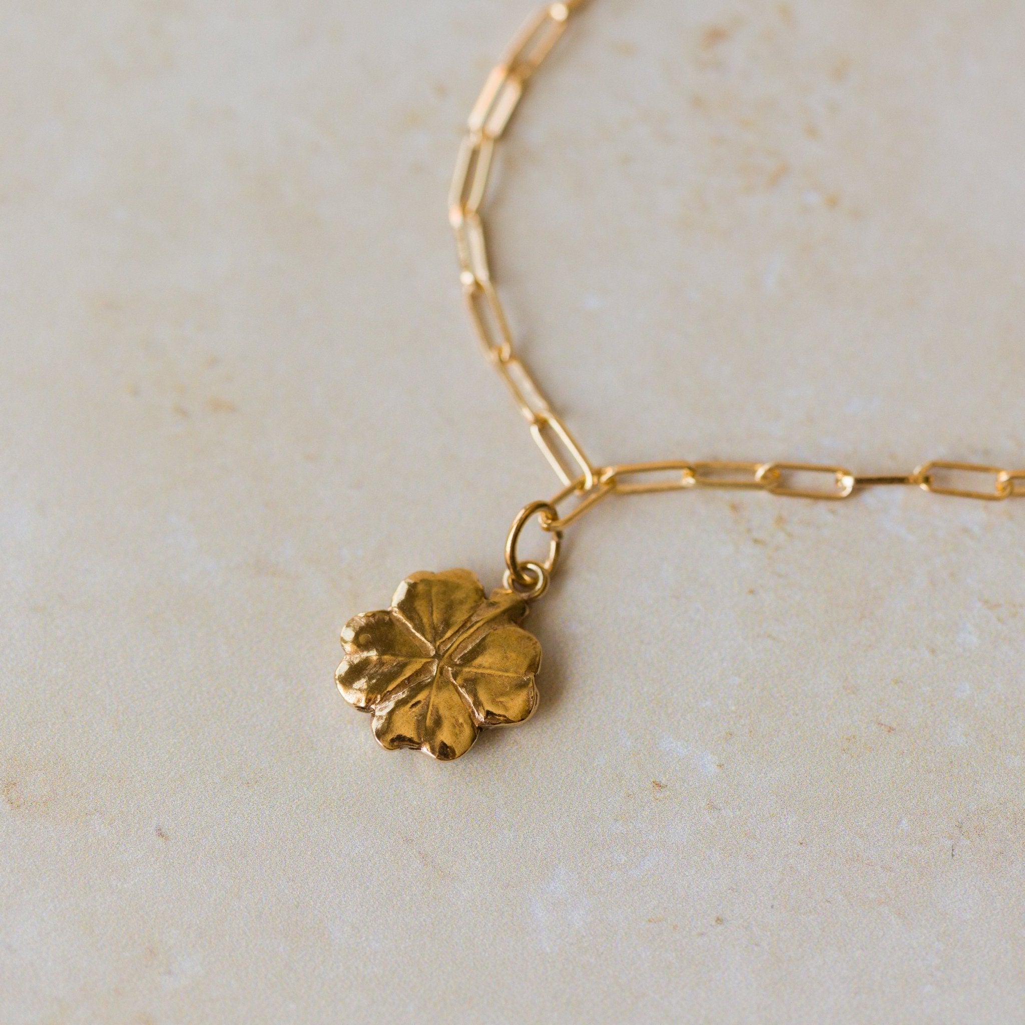 close-up of 18ct gold vermeil four-leaf clover bracelet on paperclip chain by Iris & Lolli