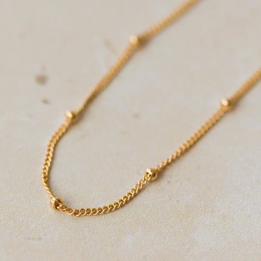close-up of 18ct gold vermeil satellite chain bracelet with delicate bead details on neutral background by Iris & Lolli