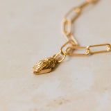 close-up of 18ct gold vermeil whelk shell charm bracelet on paperclip chain by Iris & Lolli