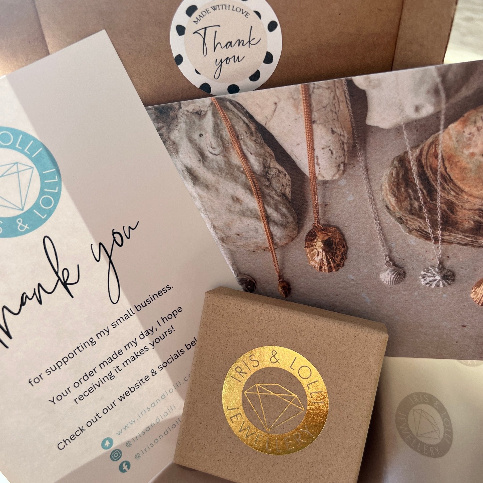 Jewelry packaging with 'Iris & Lolly' branding, including a card and box.