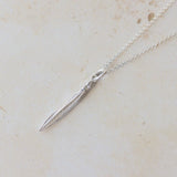 Silver necklace with a pendant on a light beige marble surface