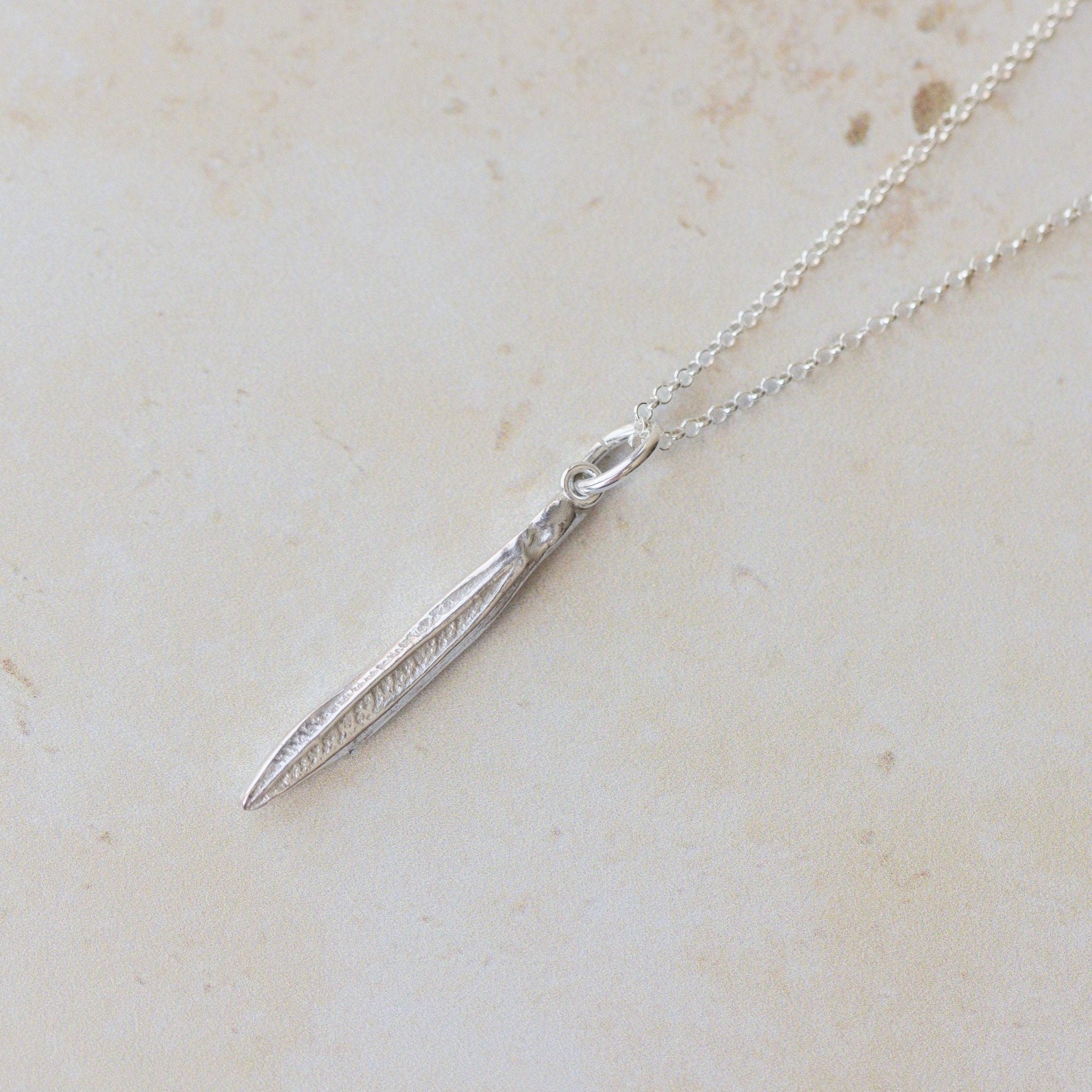 Silver necklace with a pendant on a light beige marble surface