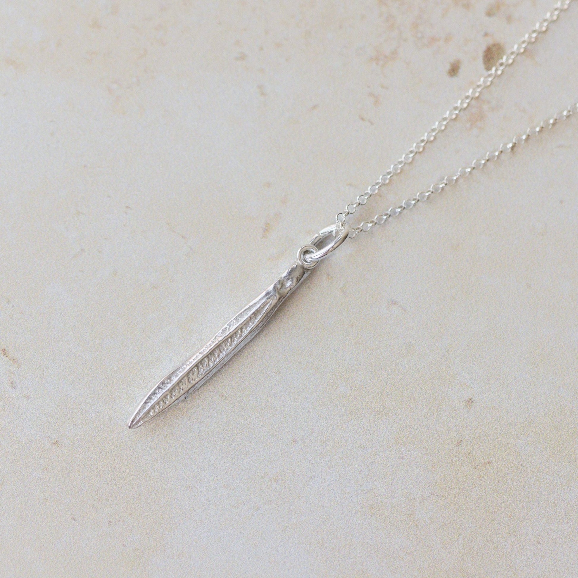 Silver necklace with a pendant on a light beige marble surface
