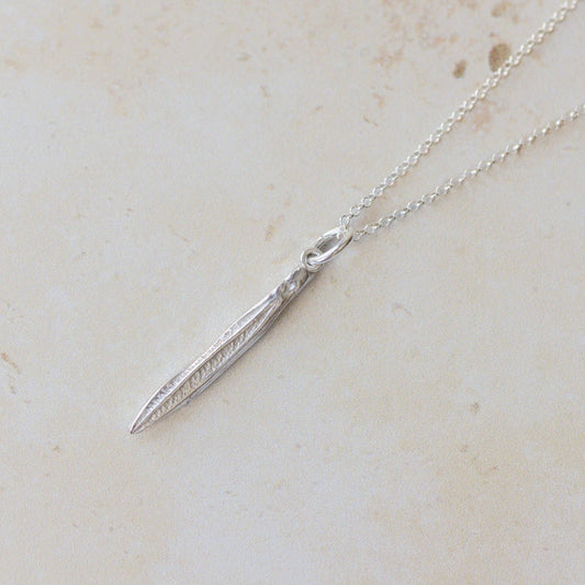 Silver necklace with a pendant on a light beige marble surface