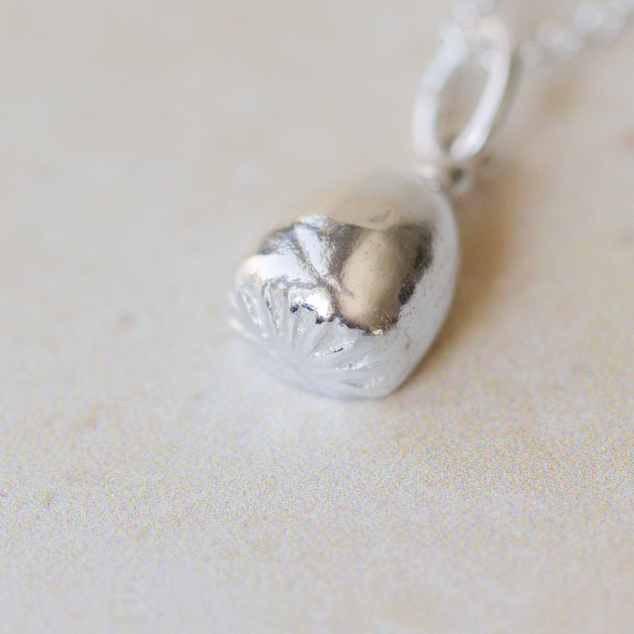 Silver pendant on a chain against a light background