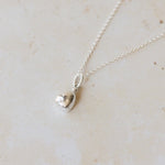 Silver necklace with a pendant on a light beige marble surface