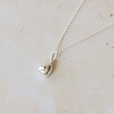 Silver necklace with a pendant on a light beige marble surface