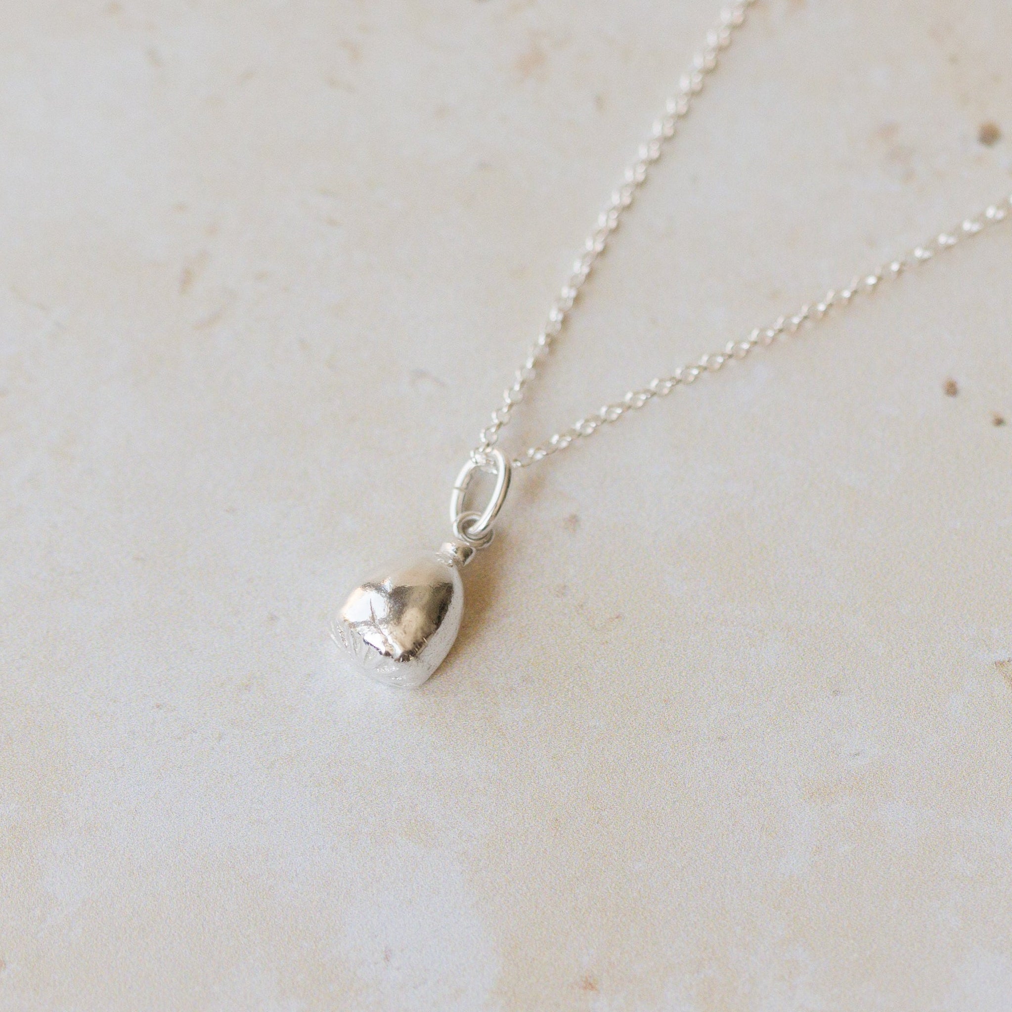 Silver necklace with a pendant on a light beige marble surface