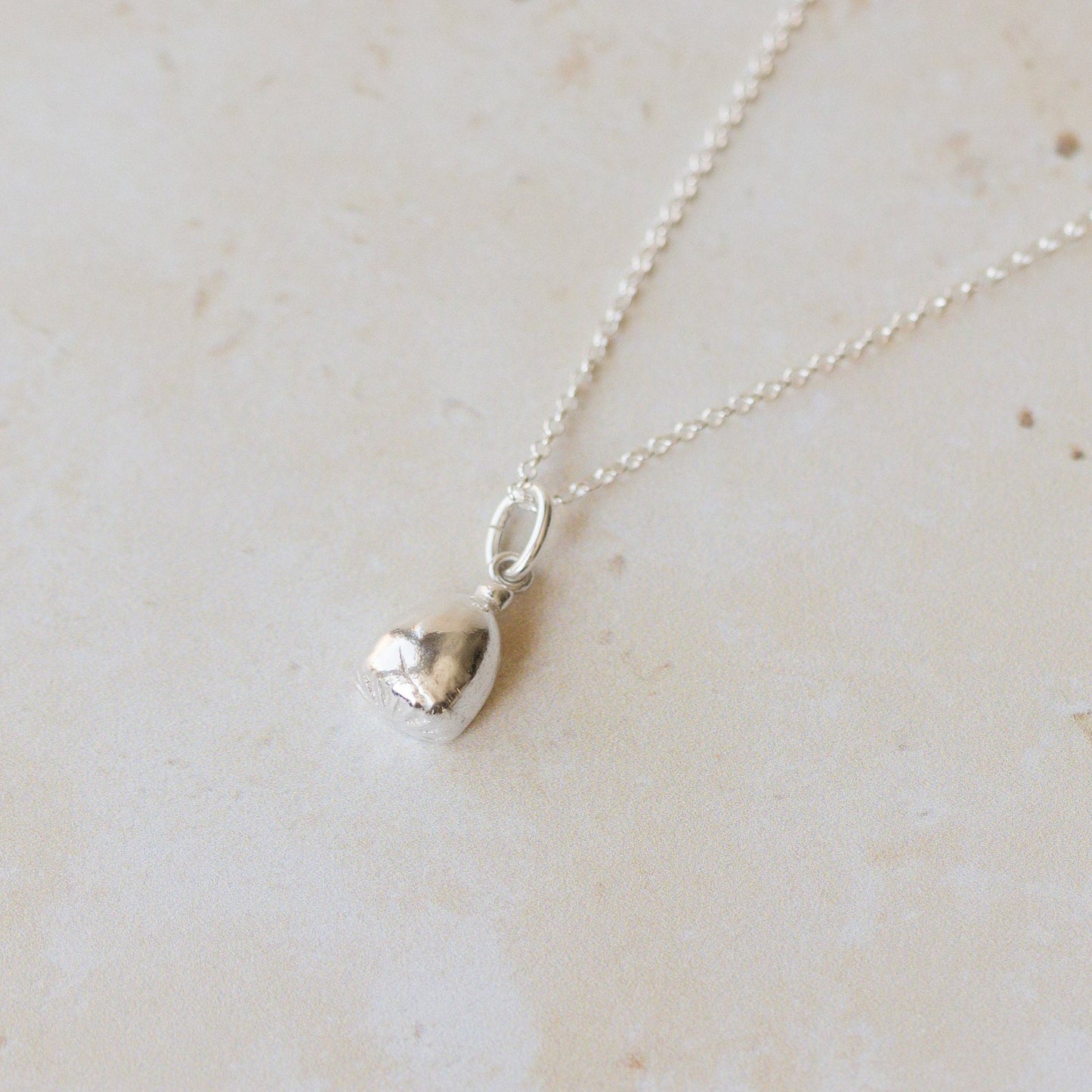 Silver necklace with a pendant on a light beige marble surface