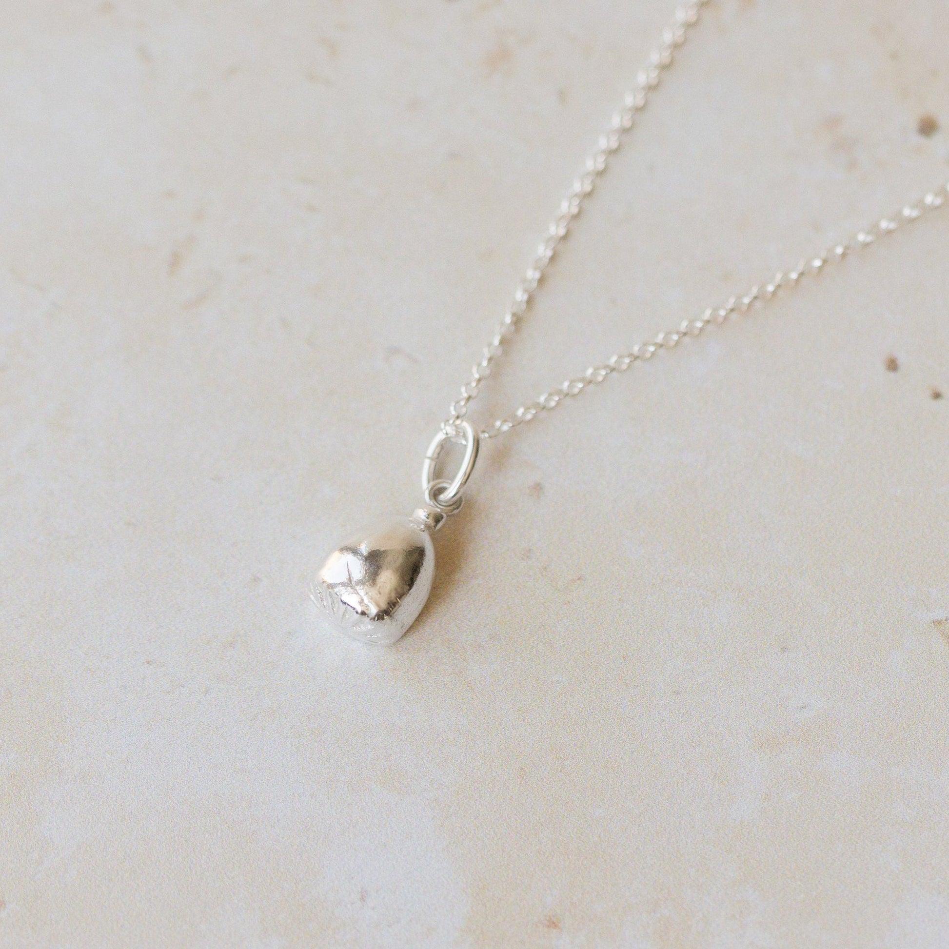 Silver necklace with a pendant on a light beige marble surface