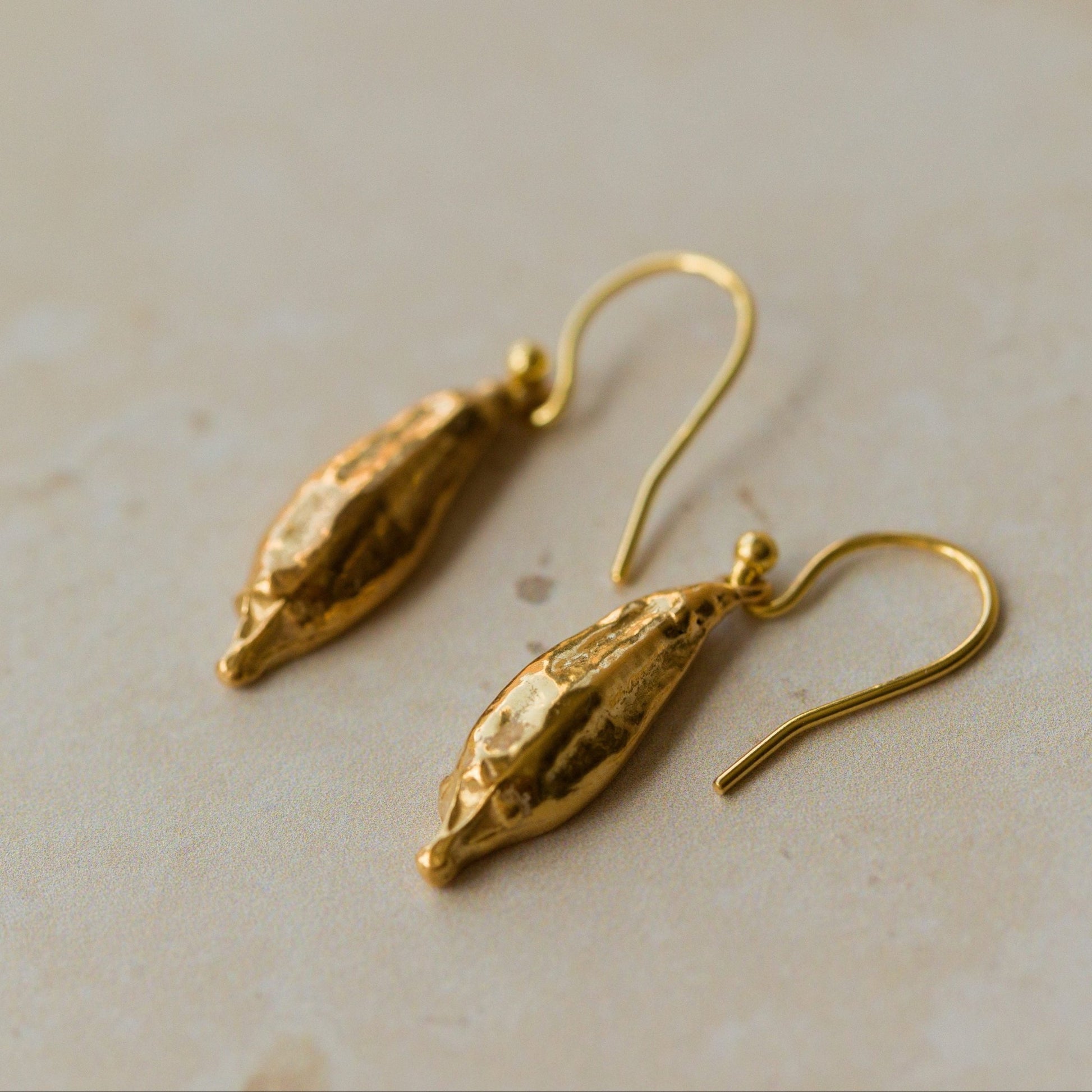 Gold earrings on a light beige surface