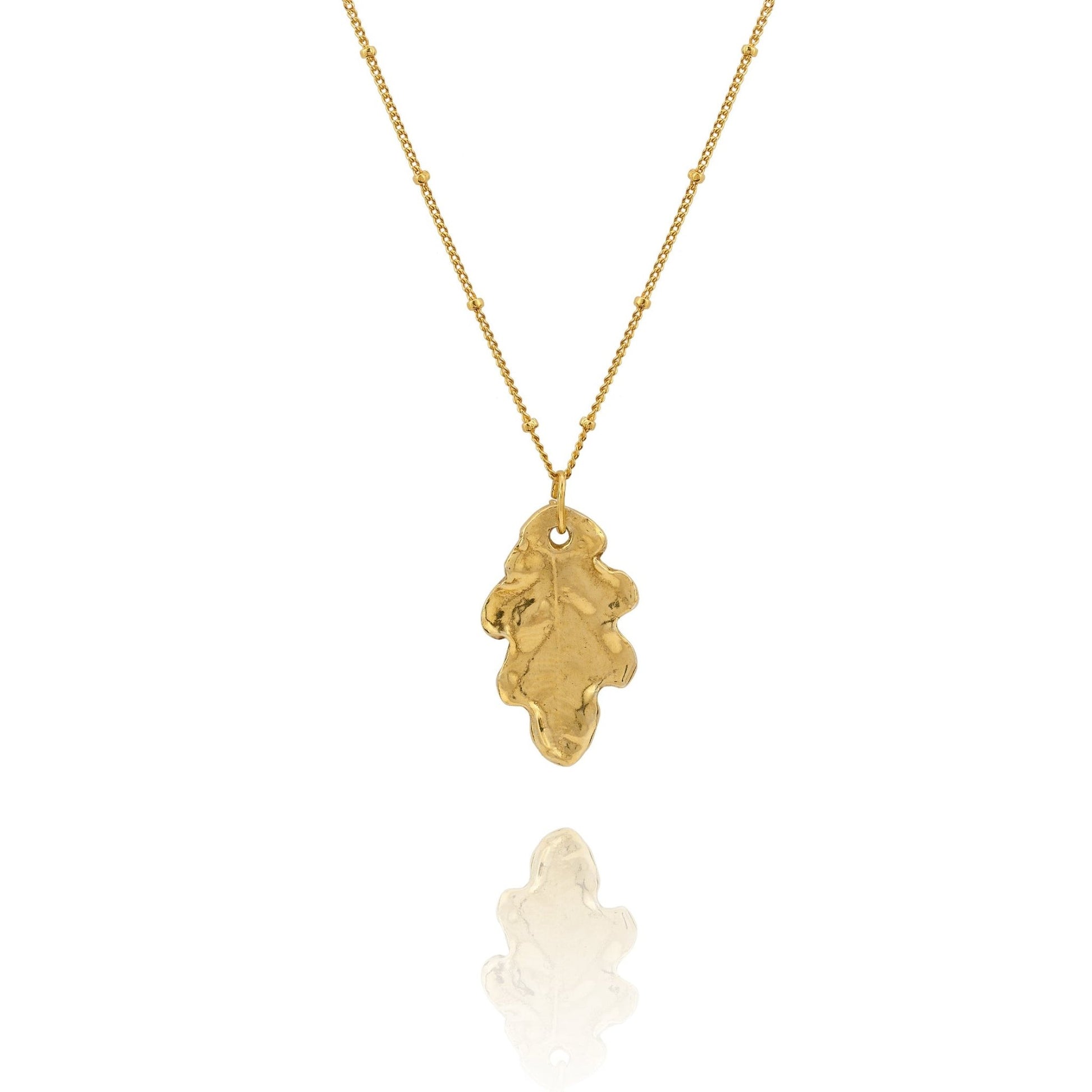 Gold necklace with a leaf-shaped pendant on a white background