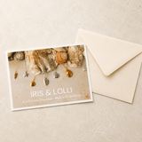 Jewelry card with 'Iris & Lolli' branding featuring necklaces and shells, accompanied by a beige envelope on a textured beige background.