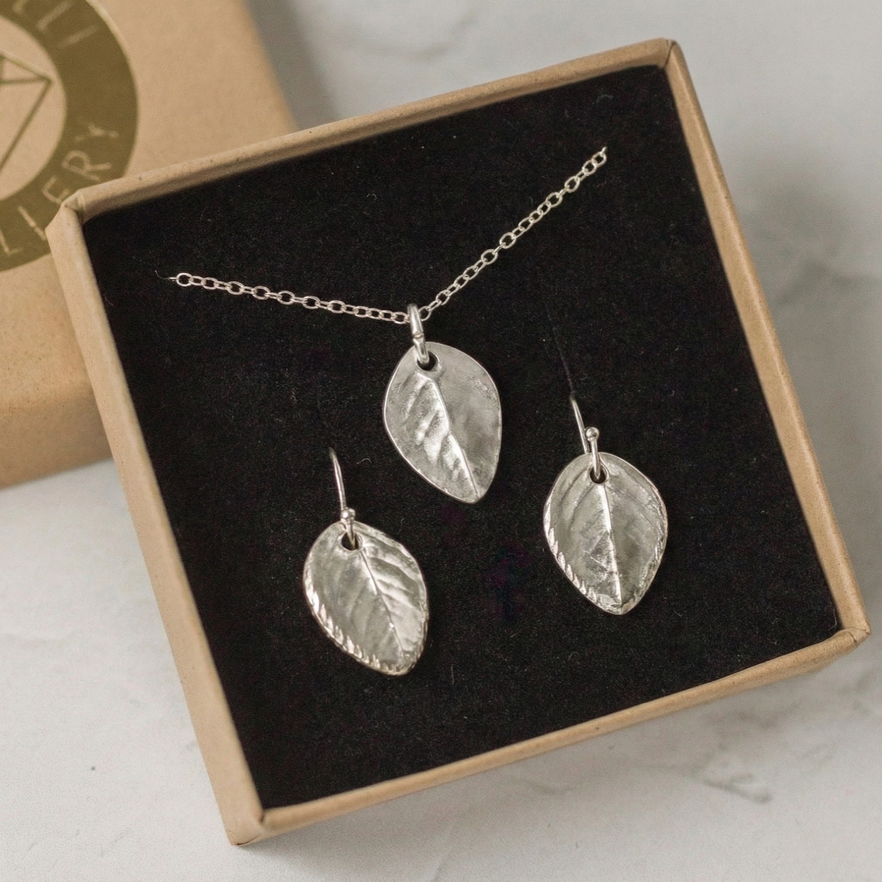 Handmade silver rose leaf necklace and earring set displayed in eco-friendly gift packaging
