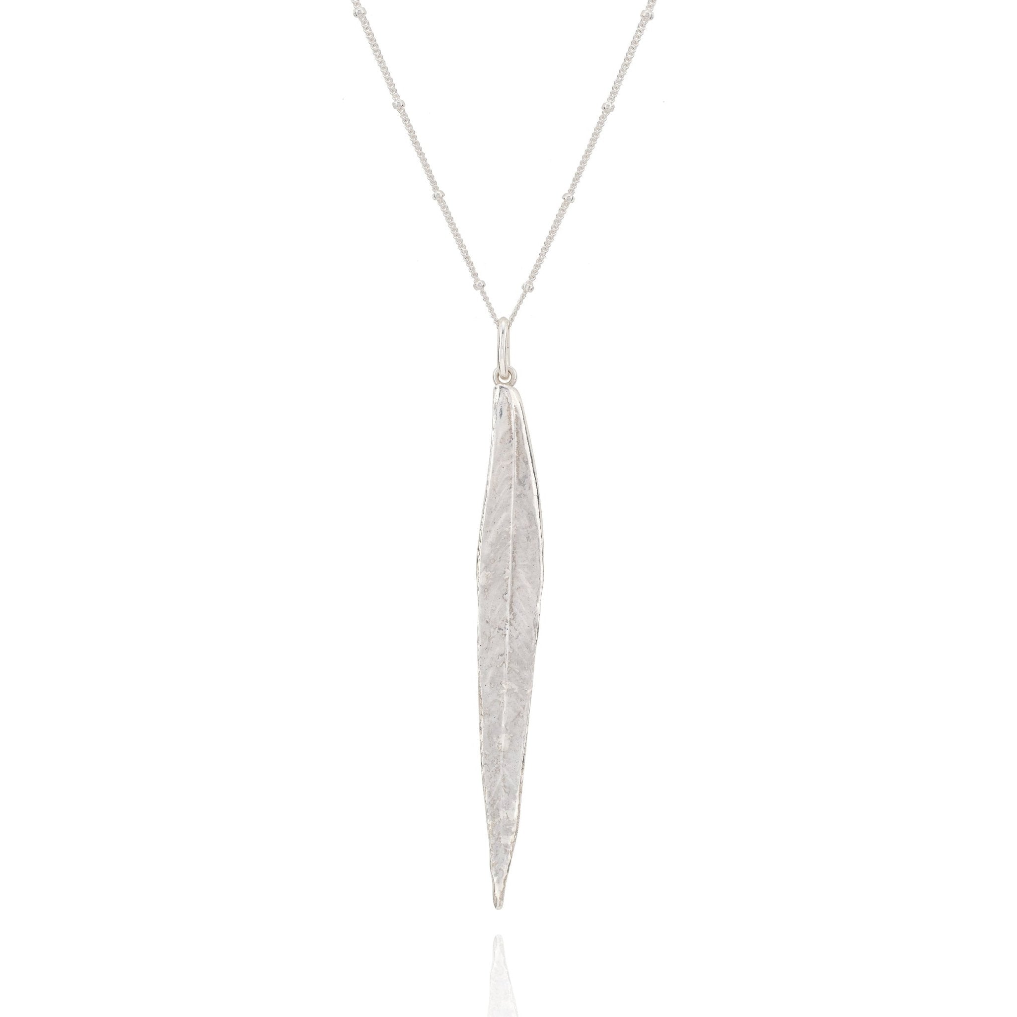Silver necklace with a long, thin pendant on a white background
