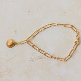 gold cockle shell charm bracelet with paperclip chain displayed flat on neutral background, handcrafted ocean-inspired jewellery by Iris & Lolli