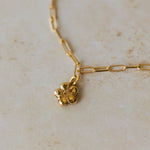 gold flower charm bracelet with paperclip chain resting on neutral stone surface, handcrafted floral jewellery by Iris & Lolli