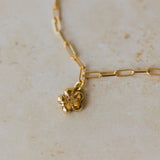 gold flower charm bracelet with paperclip chain resting on neutral stone surface, handcrafted floral jewellery by Iris & Lolli