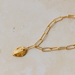 close up of gold leaf charm bracelet with paperclip chain on neutral background, handmade botanical jewellery by Iris & Lolli