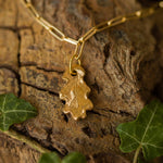 gold oak leaf charm bracelet photographed on textured bark with ivy leaves, handcrafted nature-inspired jewellery by Iris & Lolli