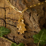 gold oak leaf charm bracelet photographed on textured bark with ivy leaves, handcrafted nature-inspired jewellery by Iris & Lolli