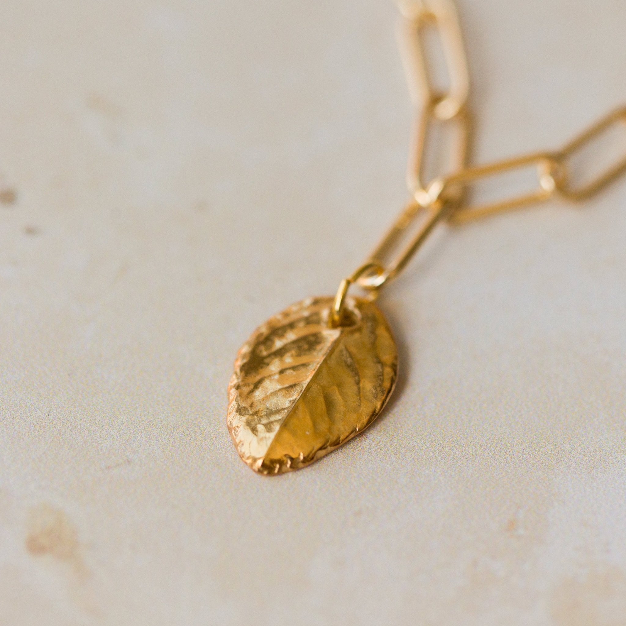 close up of gold rose leaf pendant on paperclip chain bracelet, textured handcrafted charm jewellery by Iris & Lolli