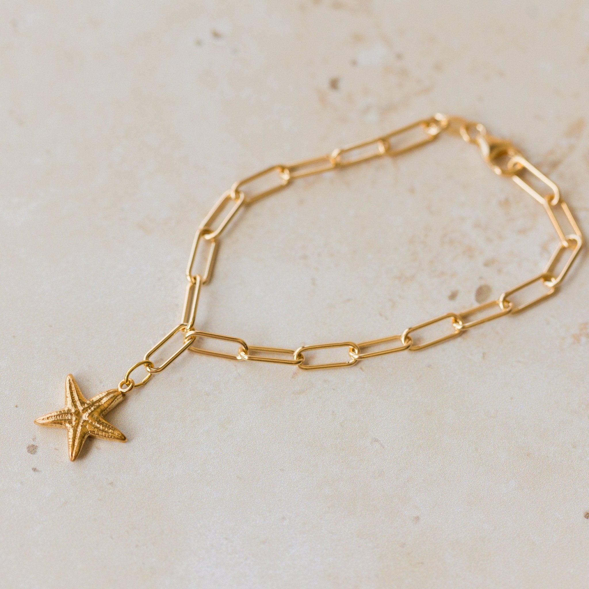 gold vermeil starfish charm bracelet with paperclip chain displayed on sandy neutral background by Iris & Lolli