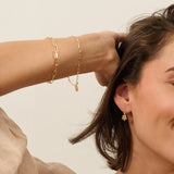 model wearing gold flower charm bracelet and matching floral drop earrings by Iris & Lolli