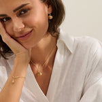 model wearing 18ct gold vermeil whelk shell charm bracelet with matching limpet shell necklace and earrings by Iris & Lolli