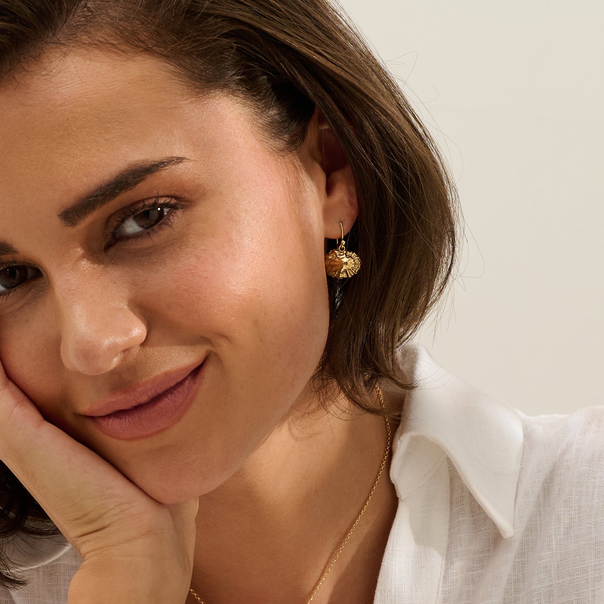 Model wearing handmade recycled gold limpet shell drop earrings by Iris and Lolli, ocean inspired and crafted in the UK