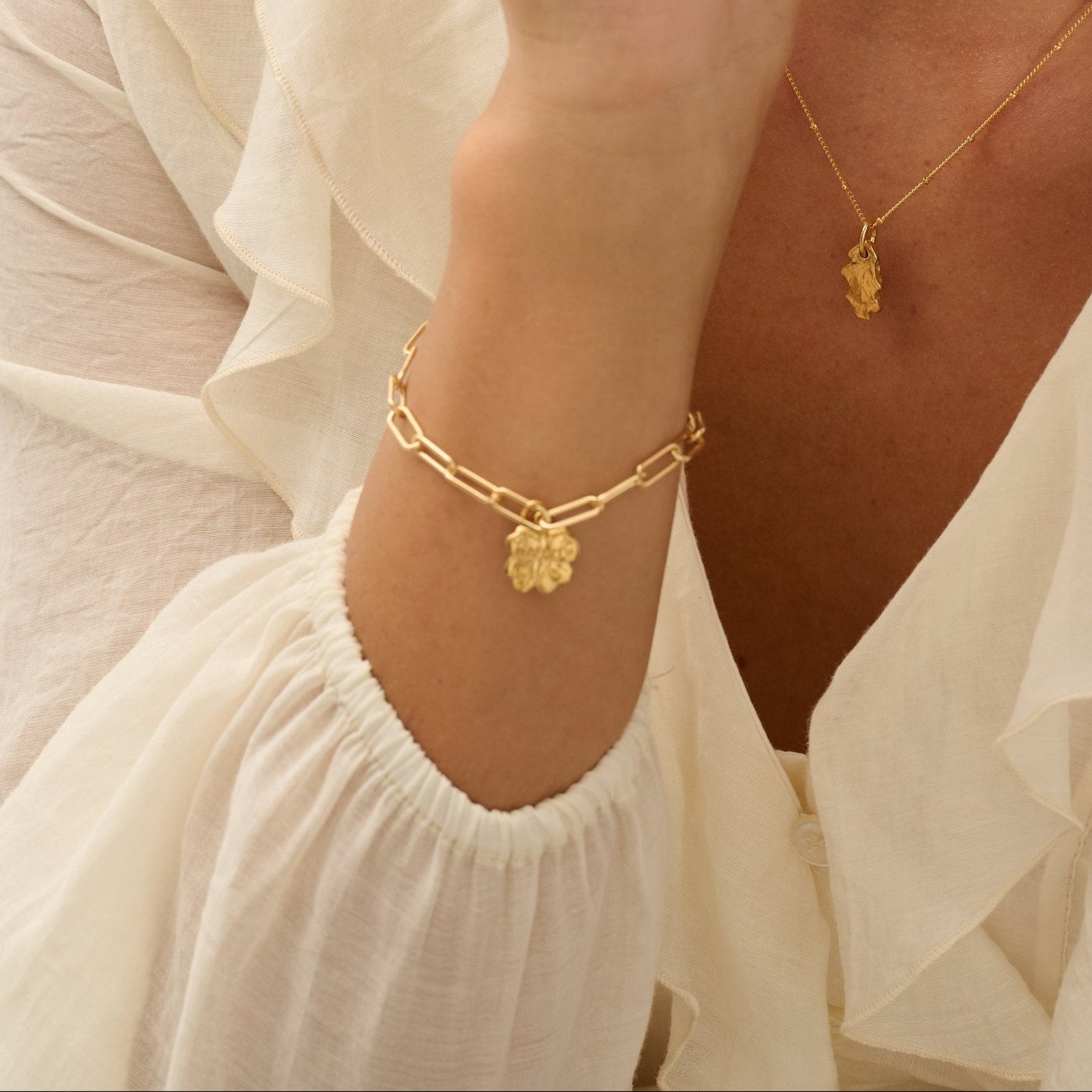 model wearing 18ct gold vermeil four-leaf clover bracelet and gold baby oak leaf pendant necklace by Iris & Lolli