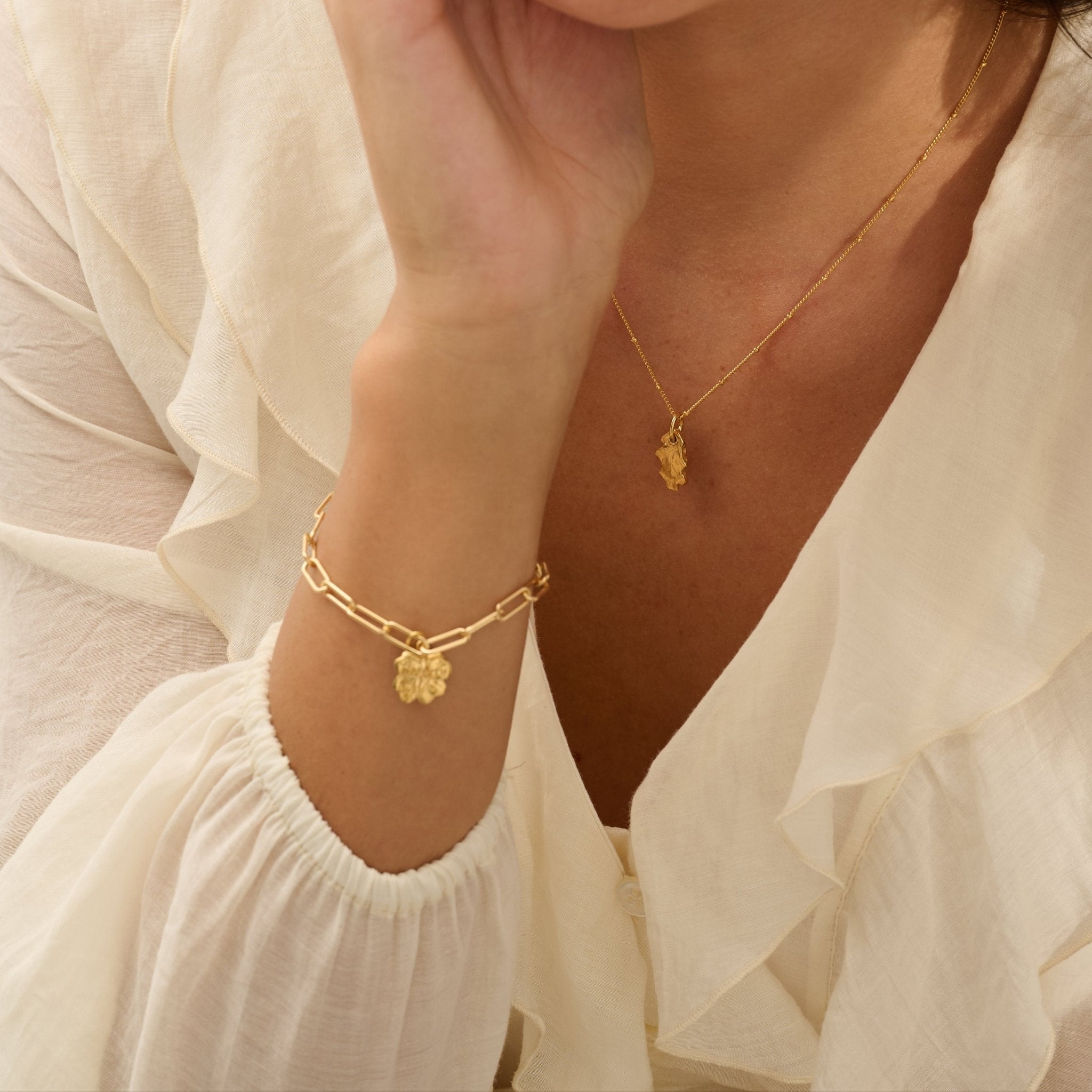 model wearing 18ct gold vermeil four-leaf clover bracelet and gold baby oak leaf pendant necklace by Iris & Lolli