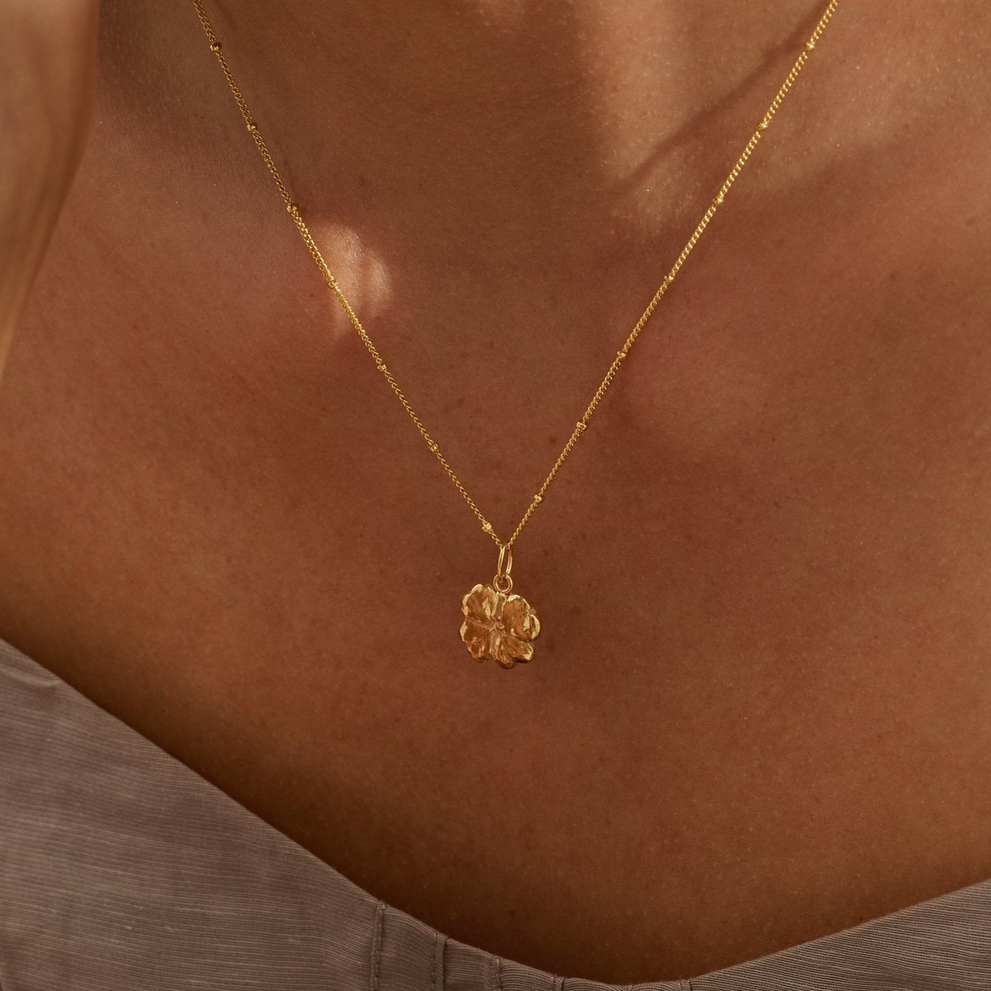 Model wearing Iris & Lolli Gold Four Leaf Clover Necklace with matching Gold Four Leaf Clover Drop Earrings handcrafted from recycled silver with an 18ct gold vermeil finish