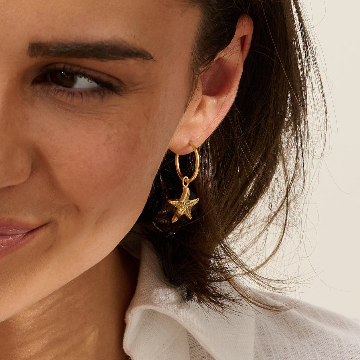 Model wearing Iris & Lolli Gold Statement Limpet Necklace paired with Gold Cockle Shell Charm Bracelet and Gold Starfish Hoop Earrings, all handcrafted from recycled silver with 18ct gold vermeil finish