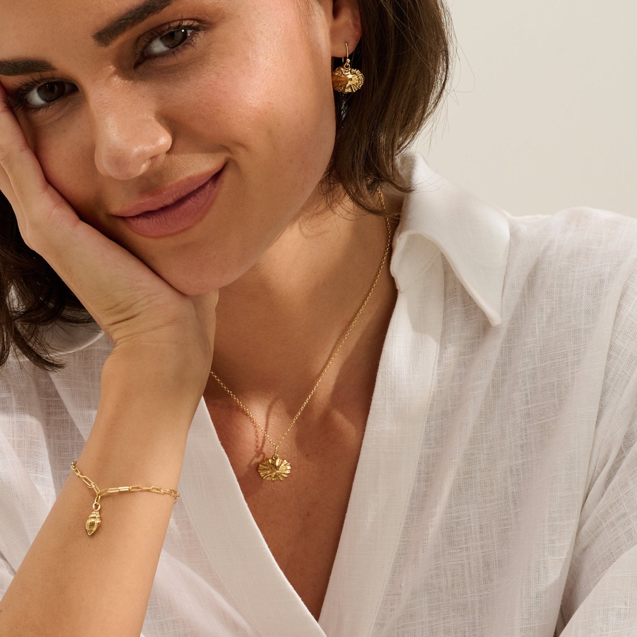 Model wearing Iris & Lolli Gold Limpet Necklace with matching Gold Limpet Earrings and Gold Whelk Shell Charm Bracelet handcrafted from recycled silver with 18ct gold vermeil finish