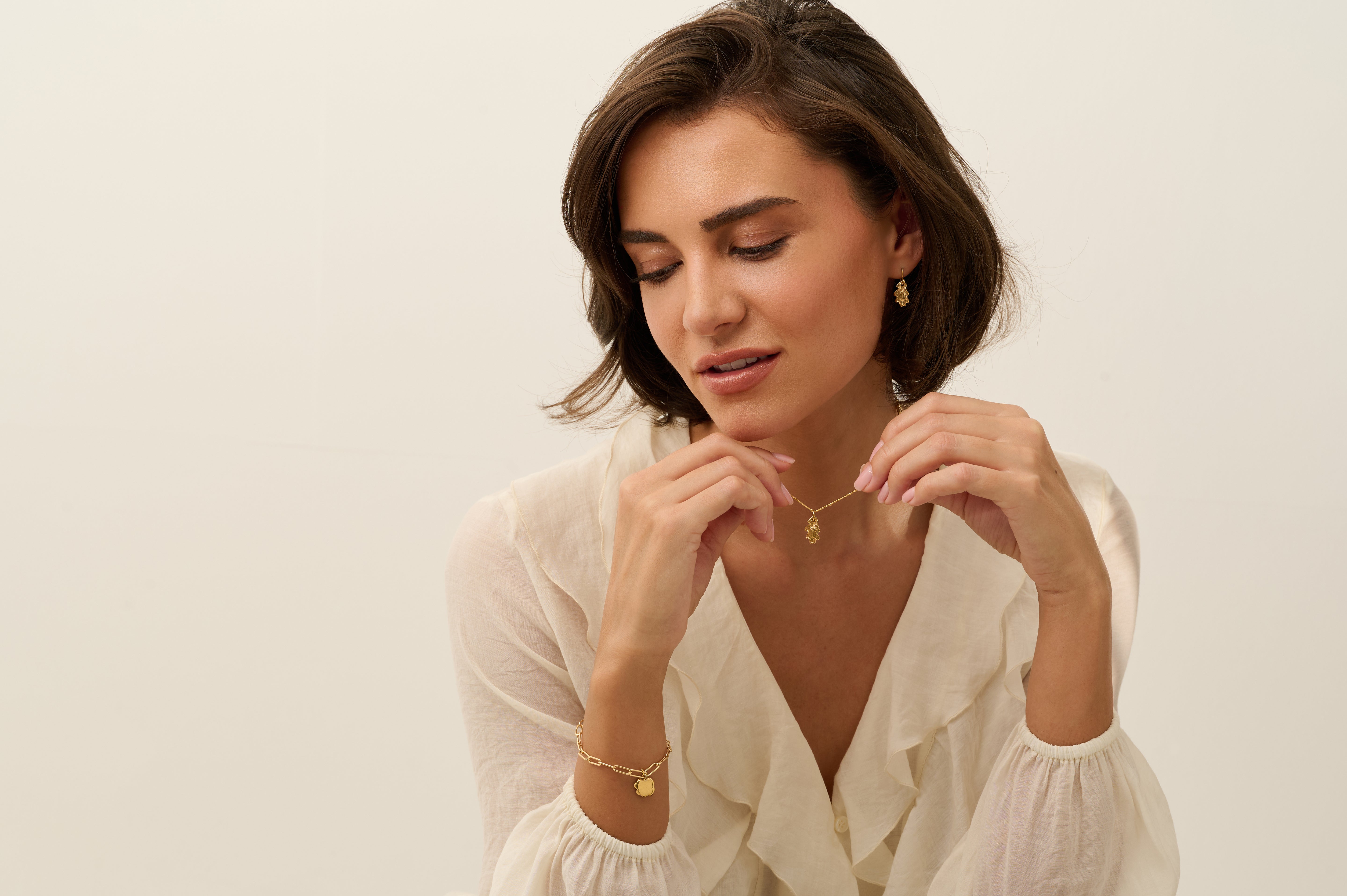 Model wearing Iris & Lolli Gold Oak Leaf Necklace with matching oak leaf Drop Earrings and Gold Charm Bracelet handcrafted from recycled silver with 18ct gold vermeil finish