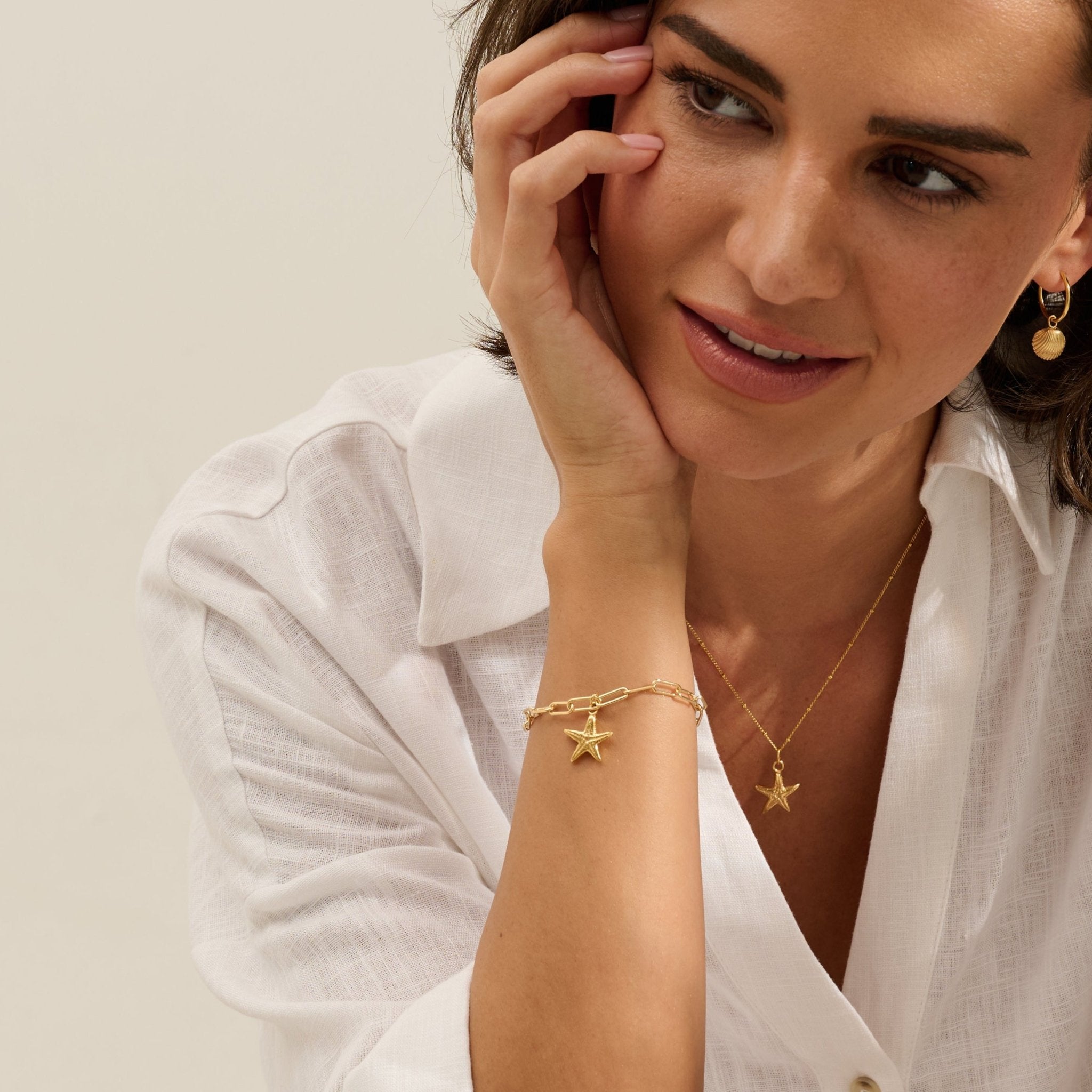 Model wearing Iris & Lolli Gold Starfish Necklace with matching Gold Starfish Charm Bracelet and Gold Cockle Shell Earrings handcrafted from recycled silver with 18ct gold vermeil finish