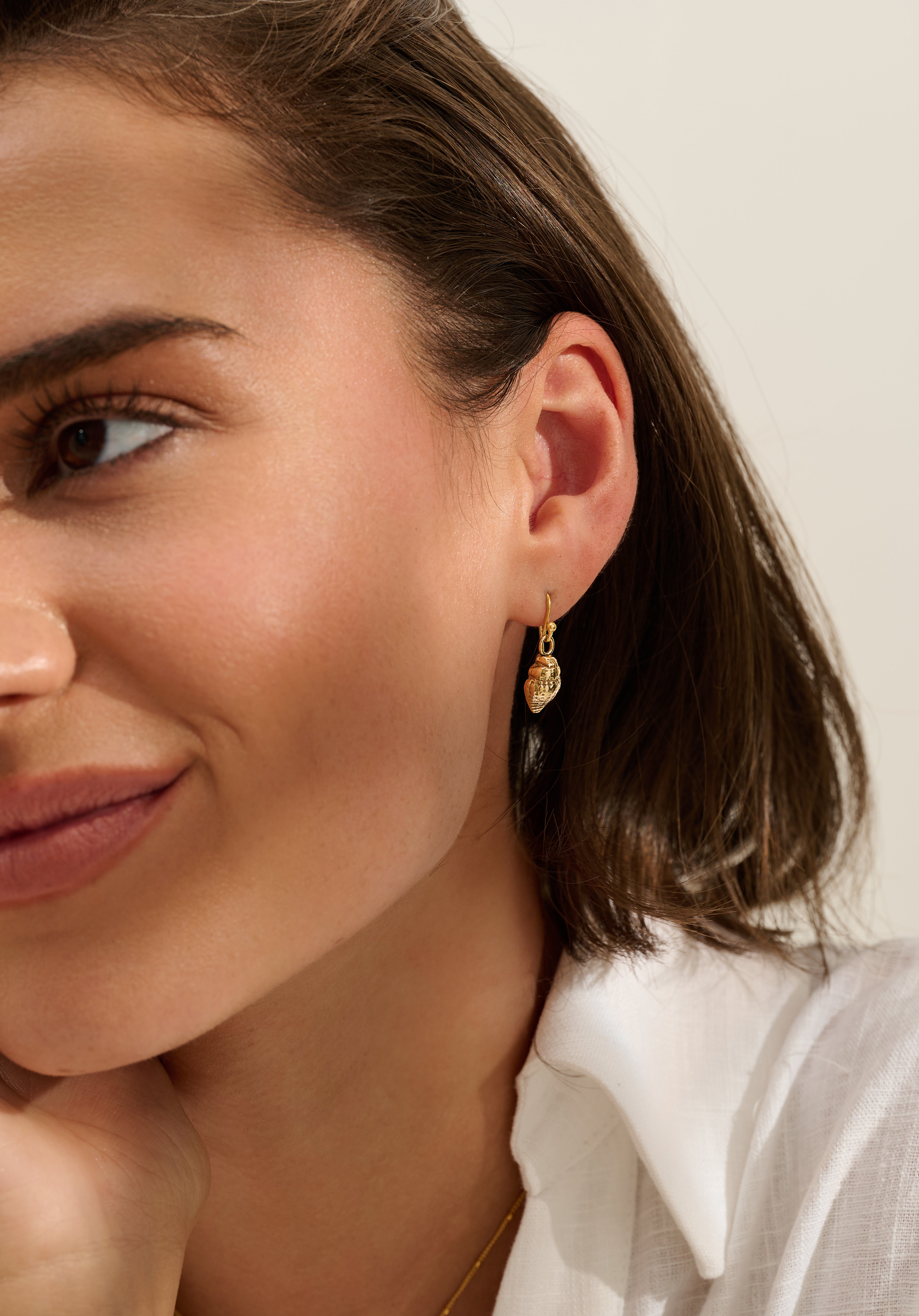 Close-up of model wearing Iris & Lolli Gold Whelk Shell Drop Earrings handcrafted from recycled silver with an 18ct gold vermeil finish
