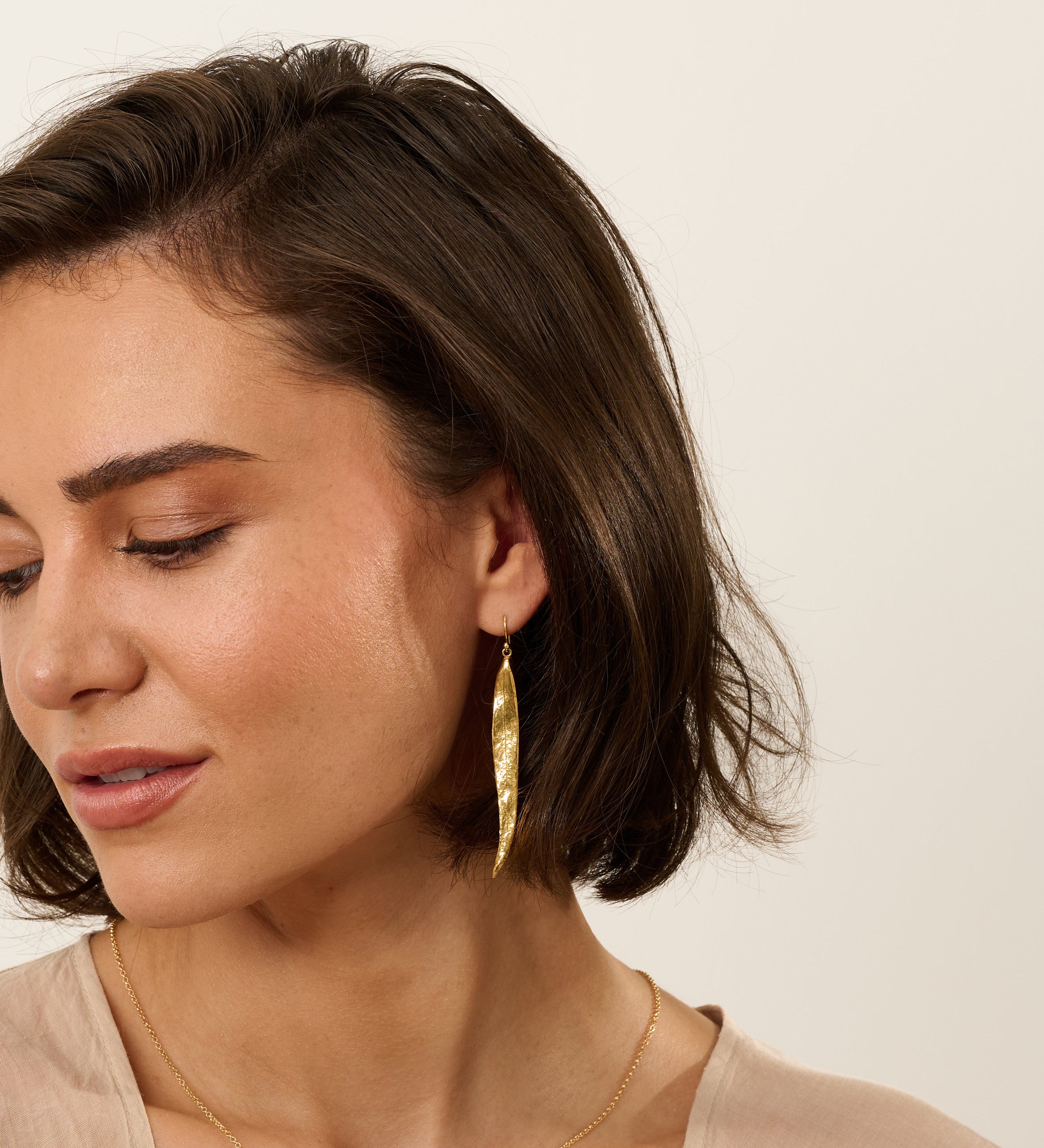 Model wearing matching gold willow leaf necklace and long gold willow leaf earrings, handcrafted botanical jewellery with organic textured leaf design.
