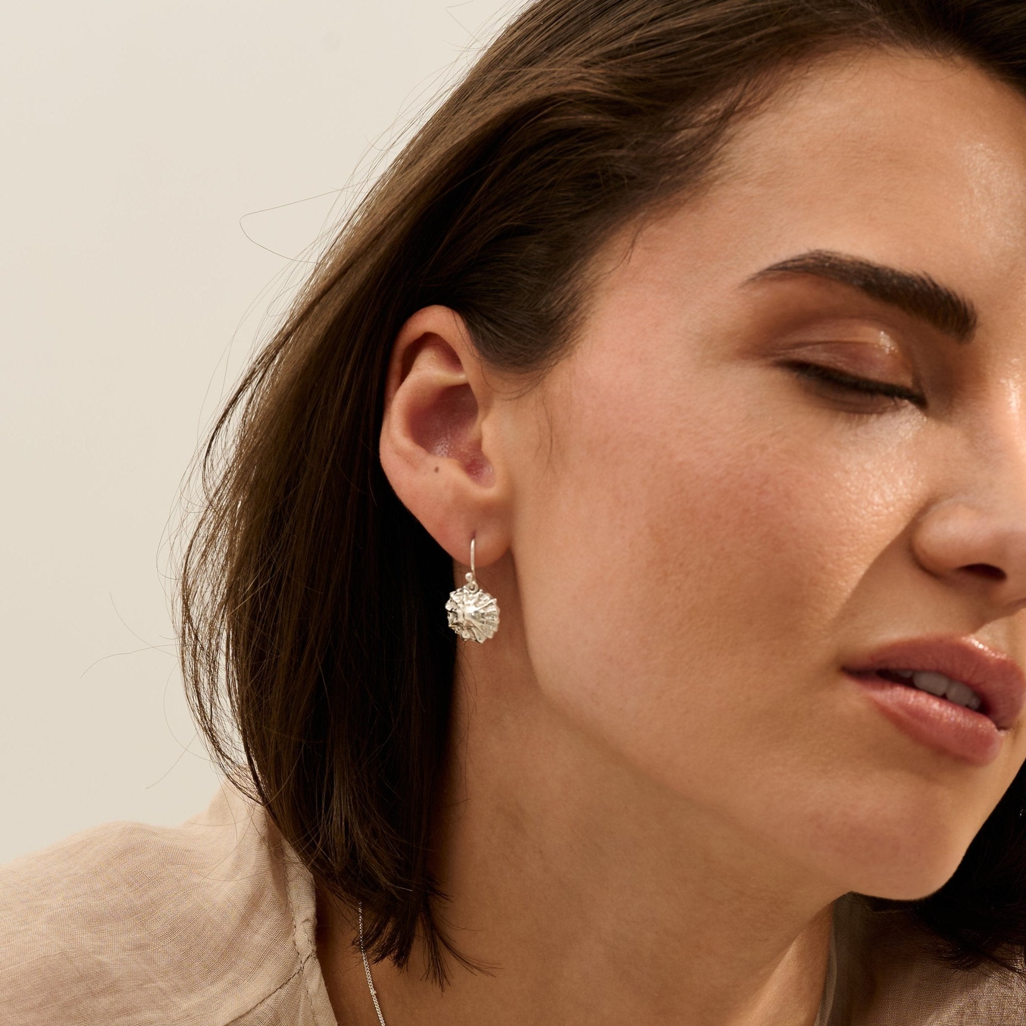 Model wearing handmade recycled silver limpet shell drop earrings by Iris and Lolli, ocean inspired and crafted in the UK