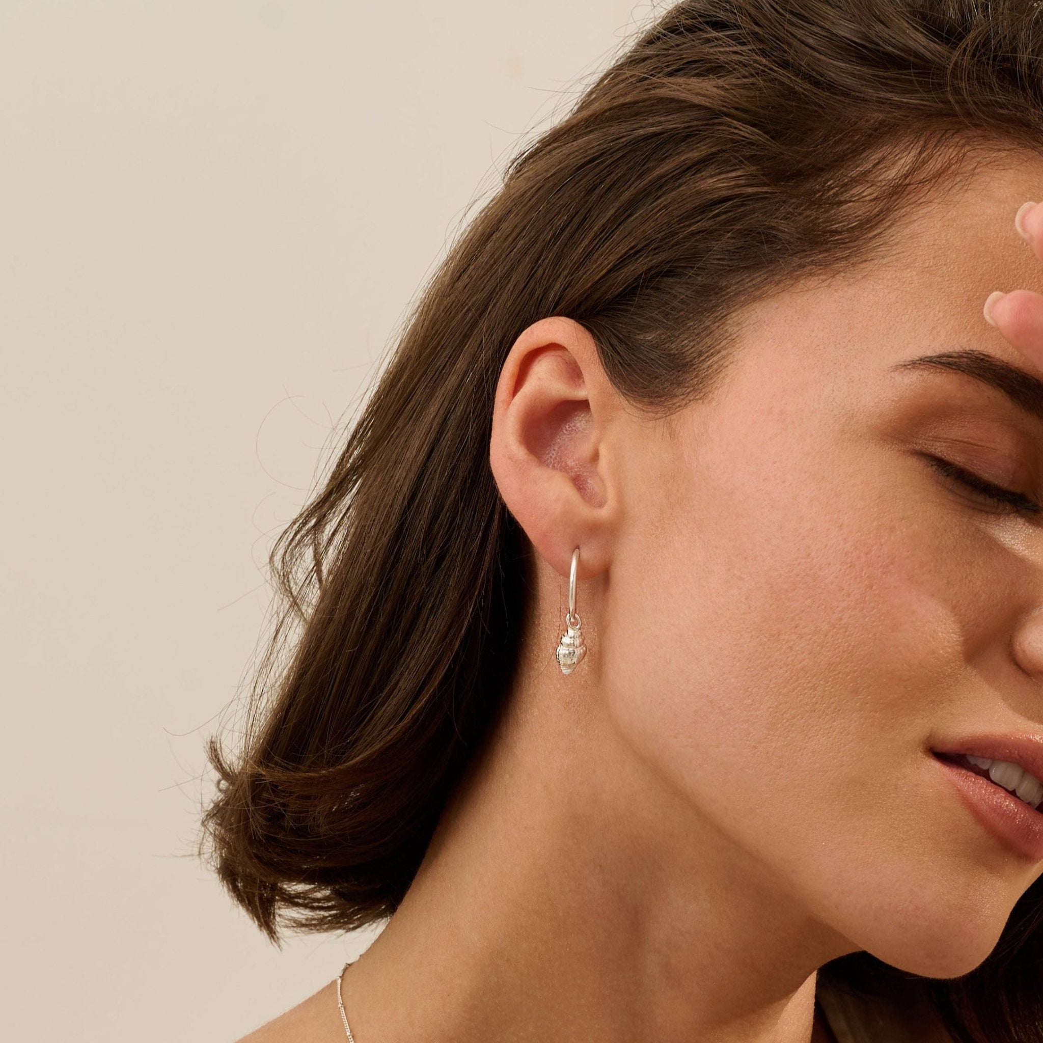 Model wearing Iris & Lolli Silver Whelk Shell Earrings handcrafted from recycled silver with natural shell texture and polished finish