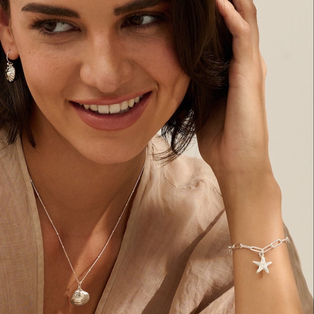 model wearing recycled silver starfish charm bracelet and Venus clam necklace by Iris & Lolli