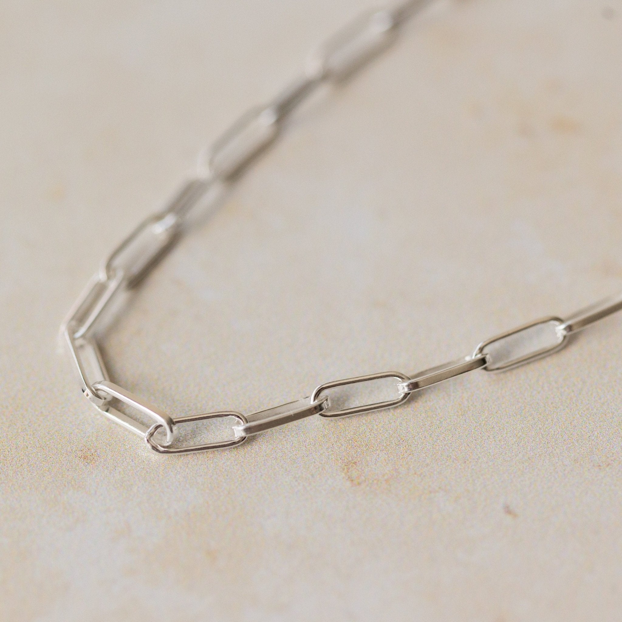 close-up of recycled silver fine paperclip chain bracelet links on neutral background by Iris & Lolli