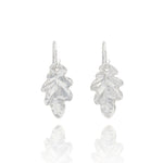 Handmade recycled silver small oak leaf drop earrings by Iris and Lolli on white background, nature inspired and crafted in the UK