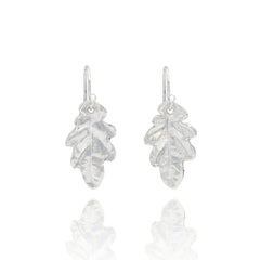 Handmade recycled silver small oak leaf drop earrings by Iris and Lolli on white background, nature inspired and crafted in the UK