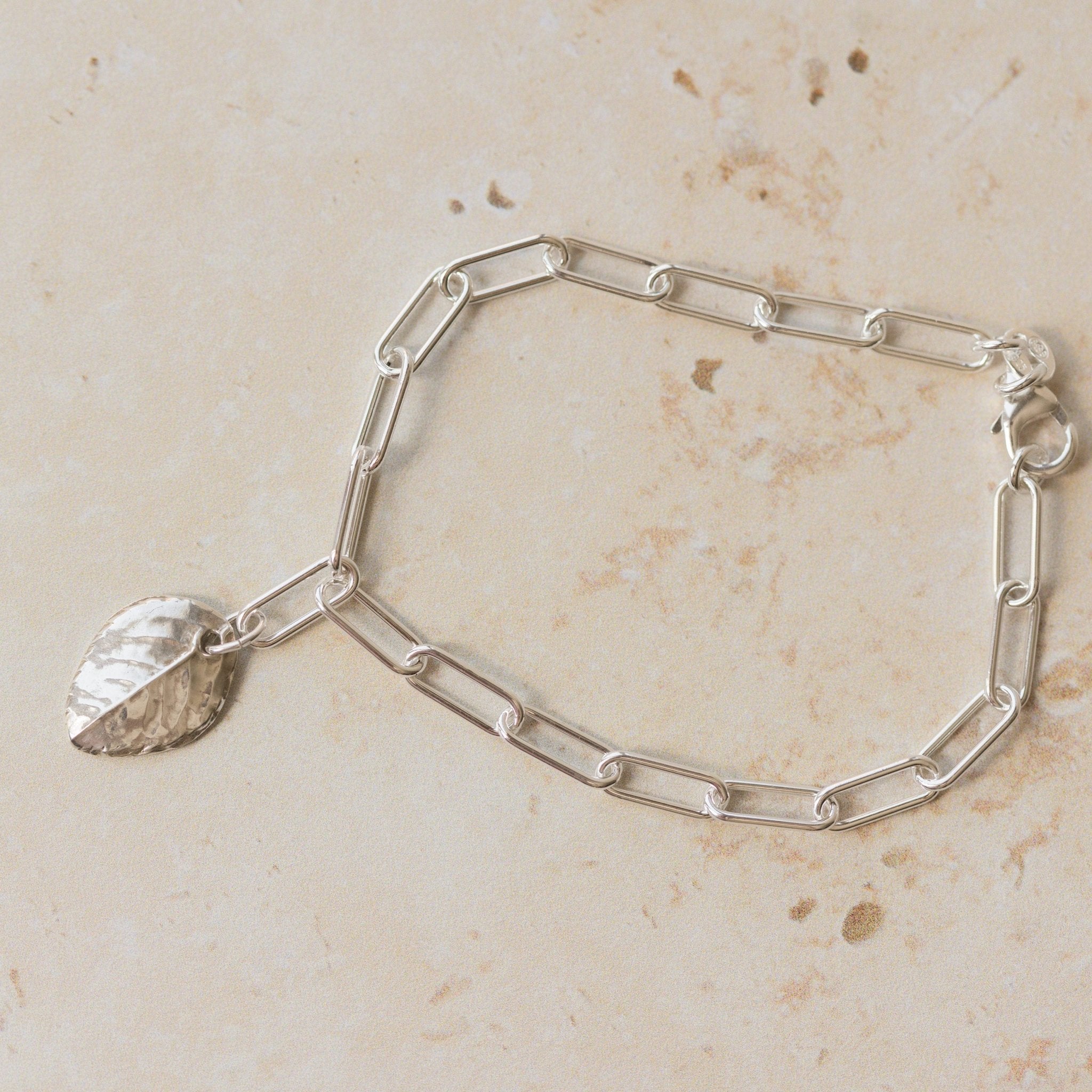 handcrafted recycled silver rose leaf charm bracelet with paperclip chain on stone background, artisan eco silver jewellery by Iris & Lolli